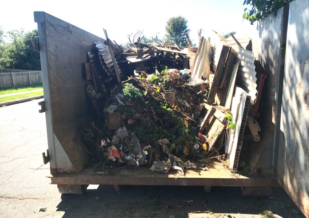 Dumpster filled with wood, metal, and brush