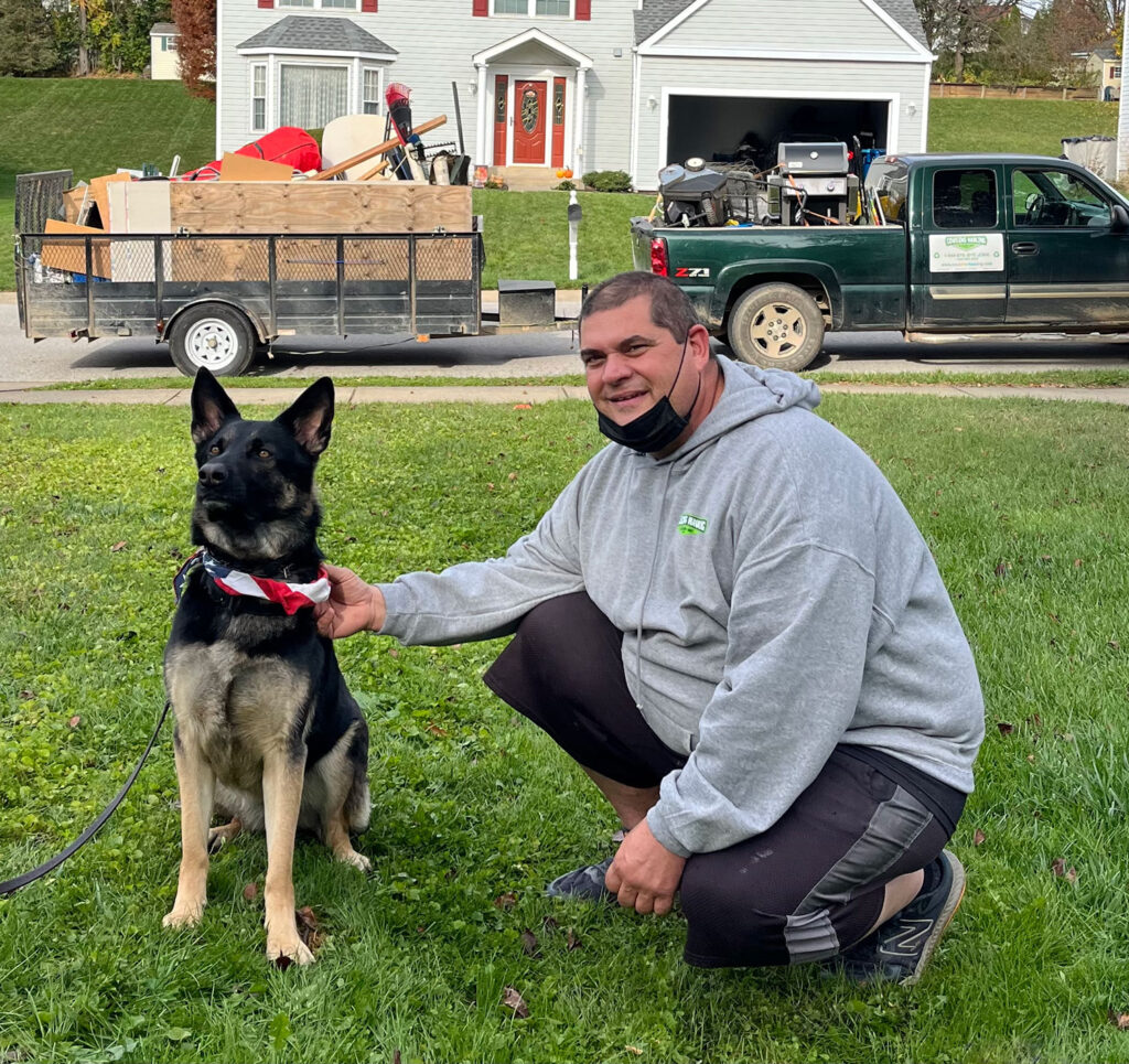 Patrick from Cousins Hauling & Cleanout sitting with Mazie, a German Shepherd